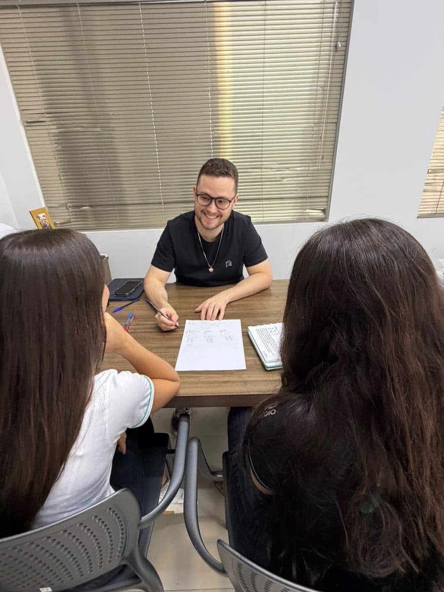 Professor do Aprova-in em aula particular, explicando exercícios para duas alunas