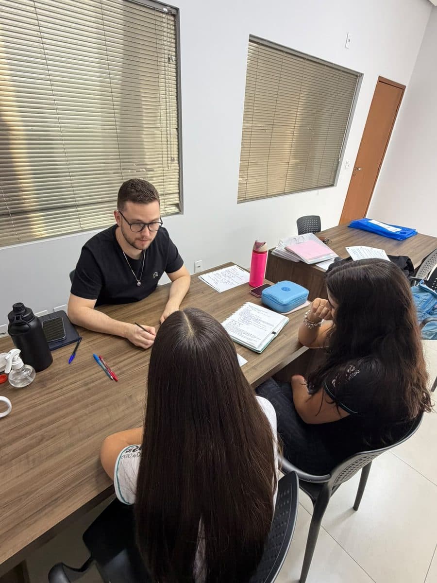 Professor do Aprova-in em aula particular, explicando exercícios para duas alunas